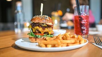 A burger with fries and a drink on a table.
