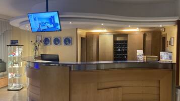 A reception area with a curved counter, a mounted television, and a wall clock.