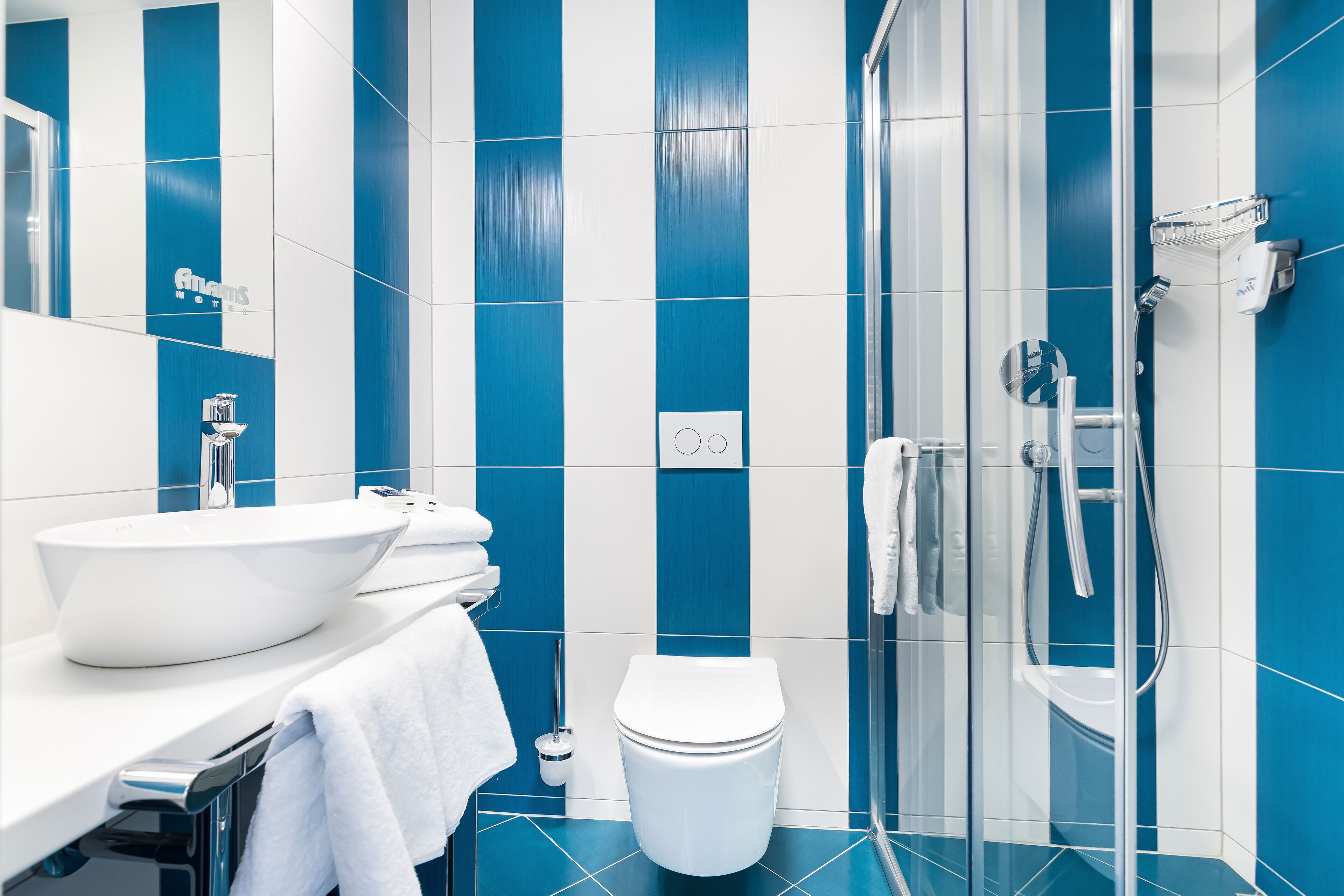 Un baño moderno con lavamanos blanco, inodoro y zona de ducha con mampara de vidrio.