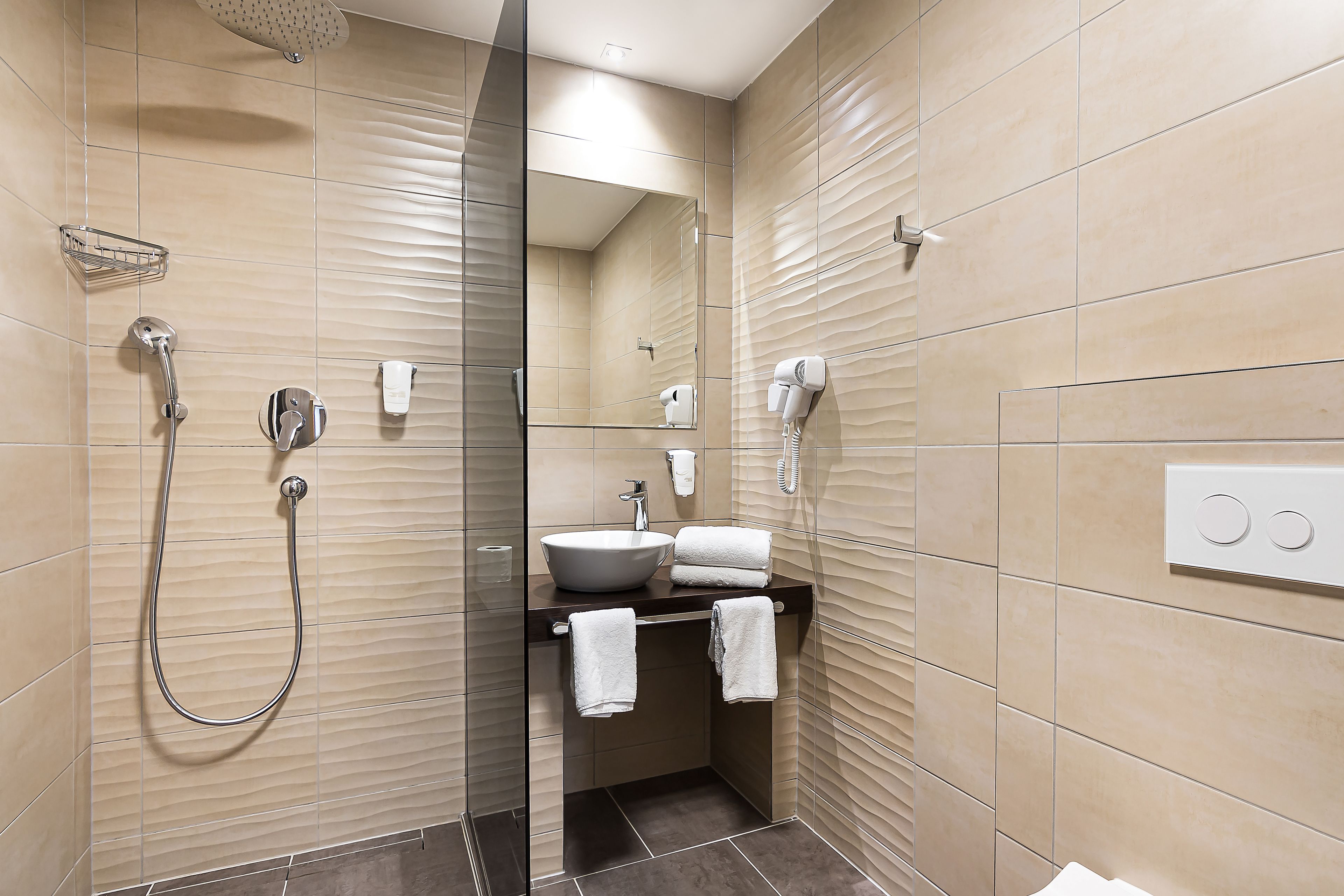 A modern bathroom with a glass-enclosed shower, a sink, and a mirror.