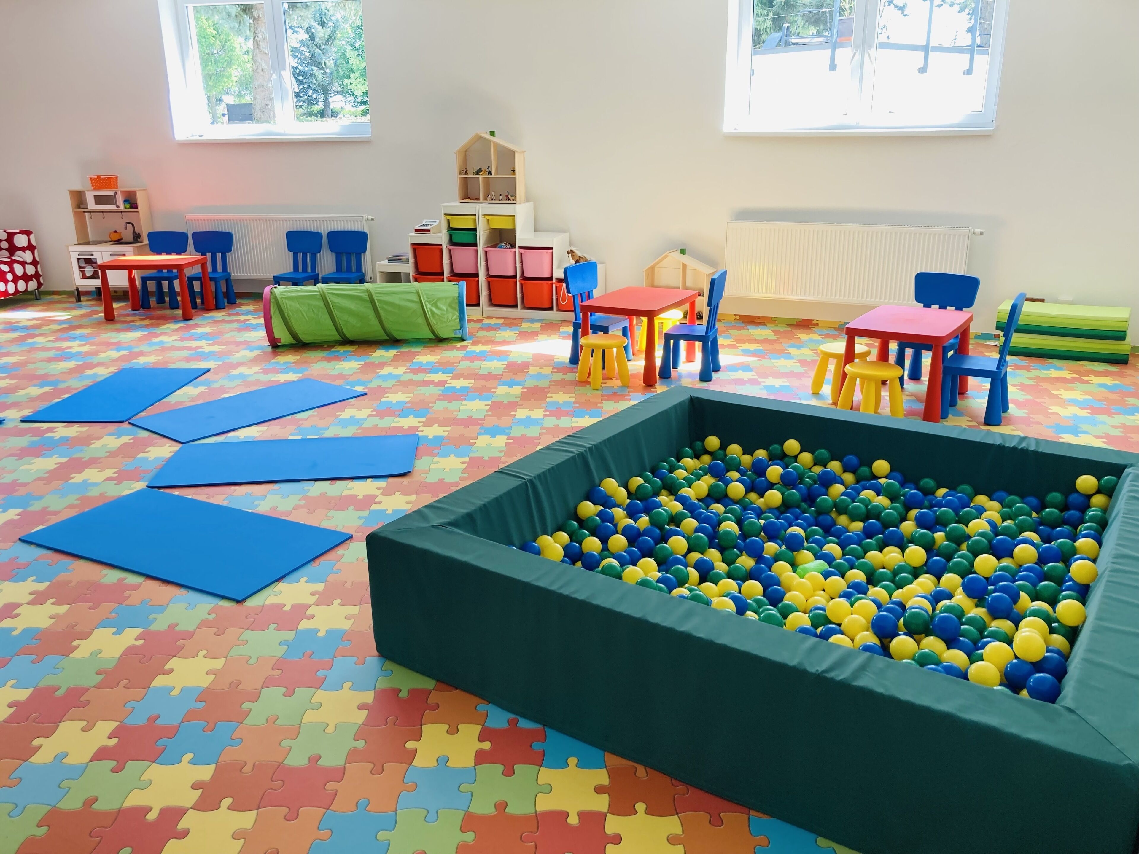 A playroom with a ball pit, colorful play mats, and various play furniture.