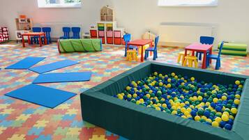 A playroom with a ball pit, colorful play mats, and various play furniture.
