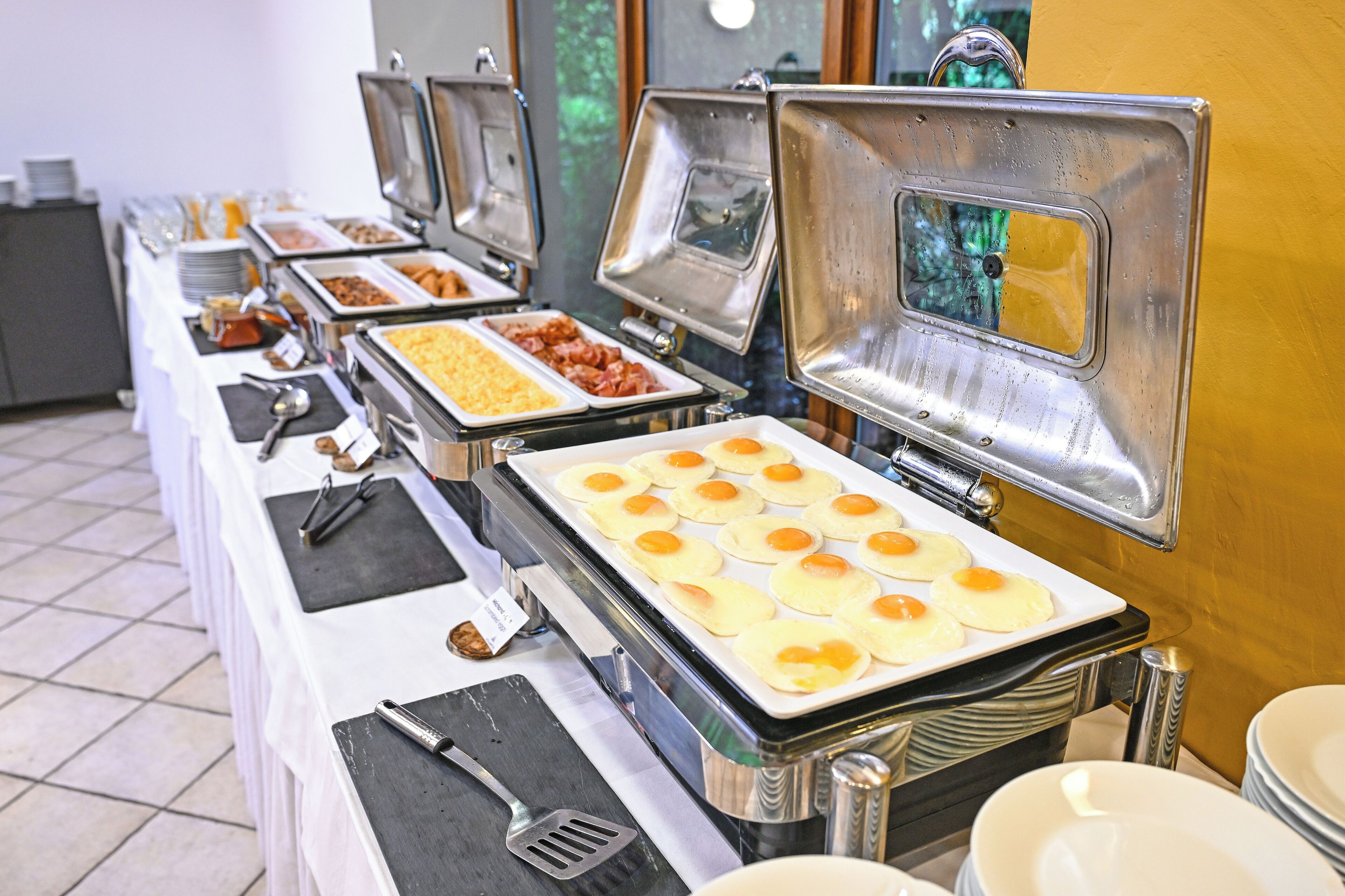 A buffet setup with various food items and utensils.