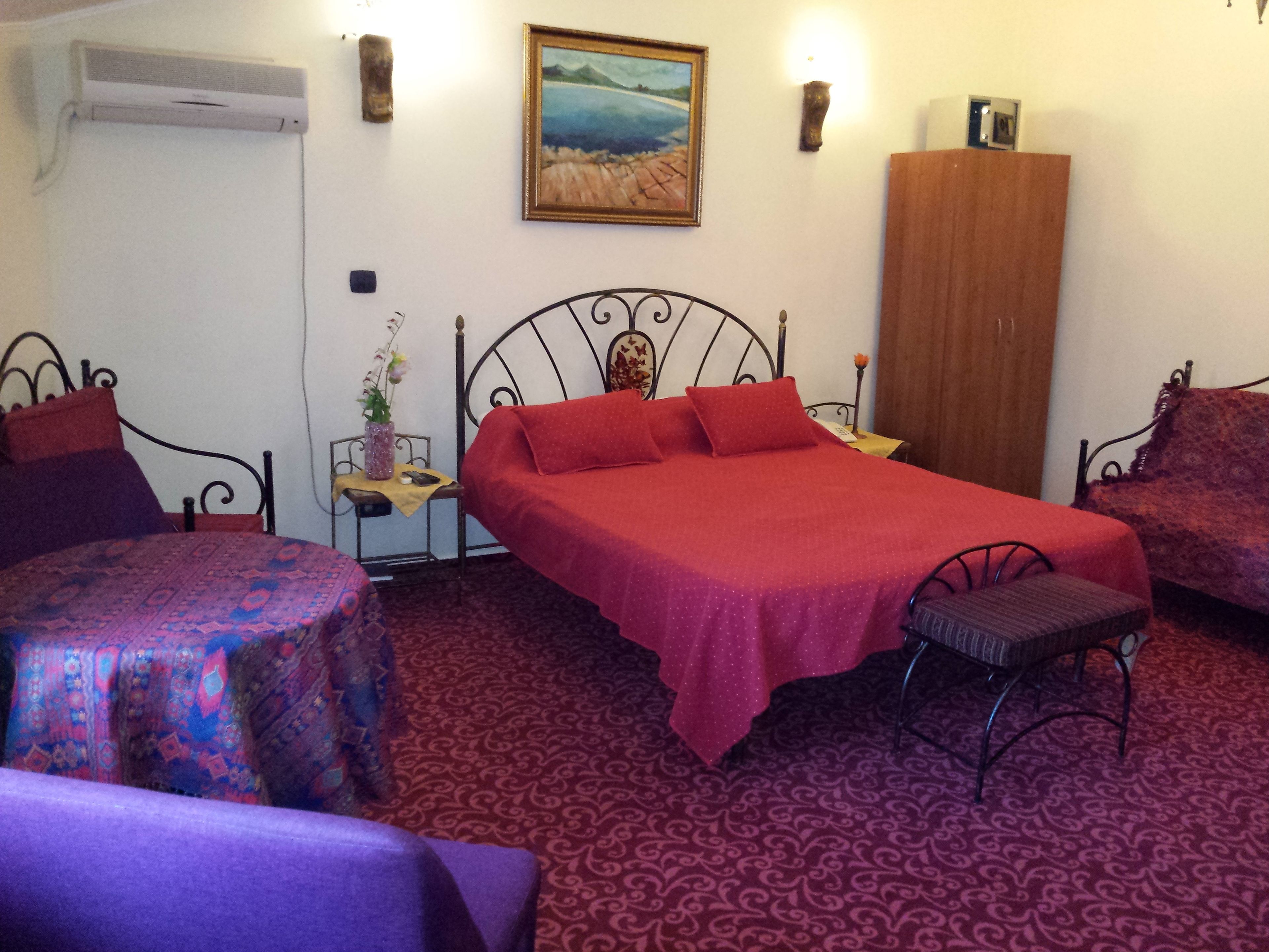 Un dormitorio con una cama, una silla, una mesita, un armario y un cuadro en la pared.
