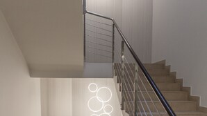 Un escalier moderne avec une rampe en métal et un luminaire aux motifs circulaires.