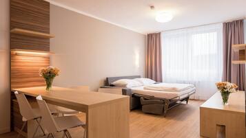 Una habitación de hotel moderna con un escritorio de madera, una cama y una pequeña zona de estar.