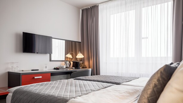 Habitación de hotel con dos camas, un escritorio, televisión de pantalla plana, cafetera y lámpara.