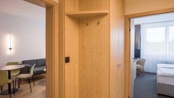 Una habitación de hotel con puerta de madera, un escritorio con silla, una cama y una pequeña mesa con sillas.