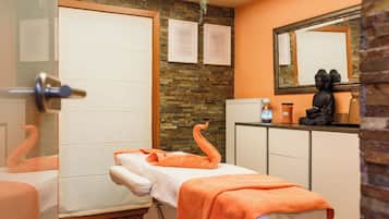 Un cuarto de spa con una camilla de masaje, una estatua y un espejo en la pared.
