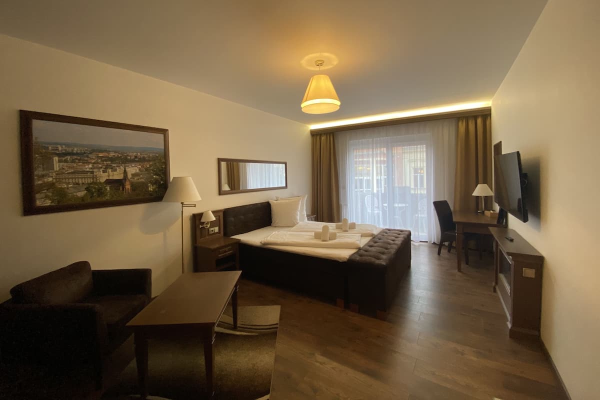 Une chambre d’hôtel avec un lit, un bureau, une chaise, une télévision et un tableau au mur.