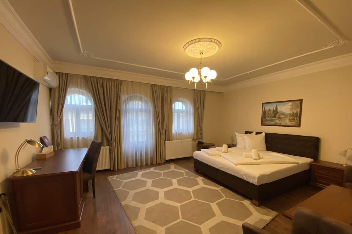 Une chambre d’hôtel avec un lit, un bureau, une chaise et un tableau au mur.