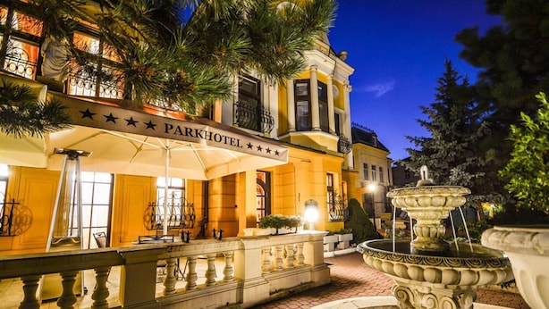 A Park Hotel with a fountain, outdoor seating, and a well-lit entrance.