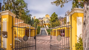 A gated entrance to a yellow building with a staircase leading to the entrance.