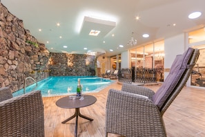 Una piscina techada, sillones reclinables de piscina