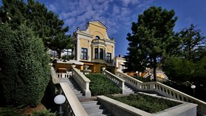A grand building with a yellow facade, multiple staircases, and a prominent entrance.