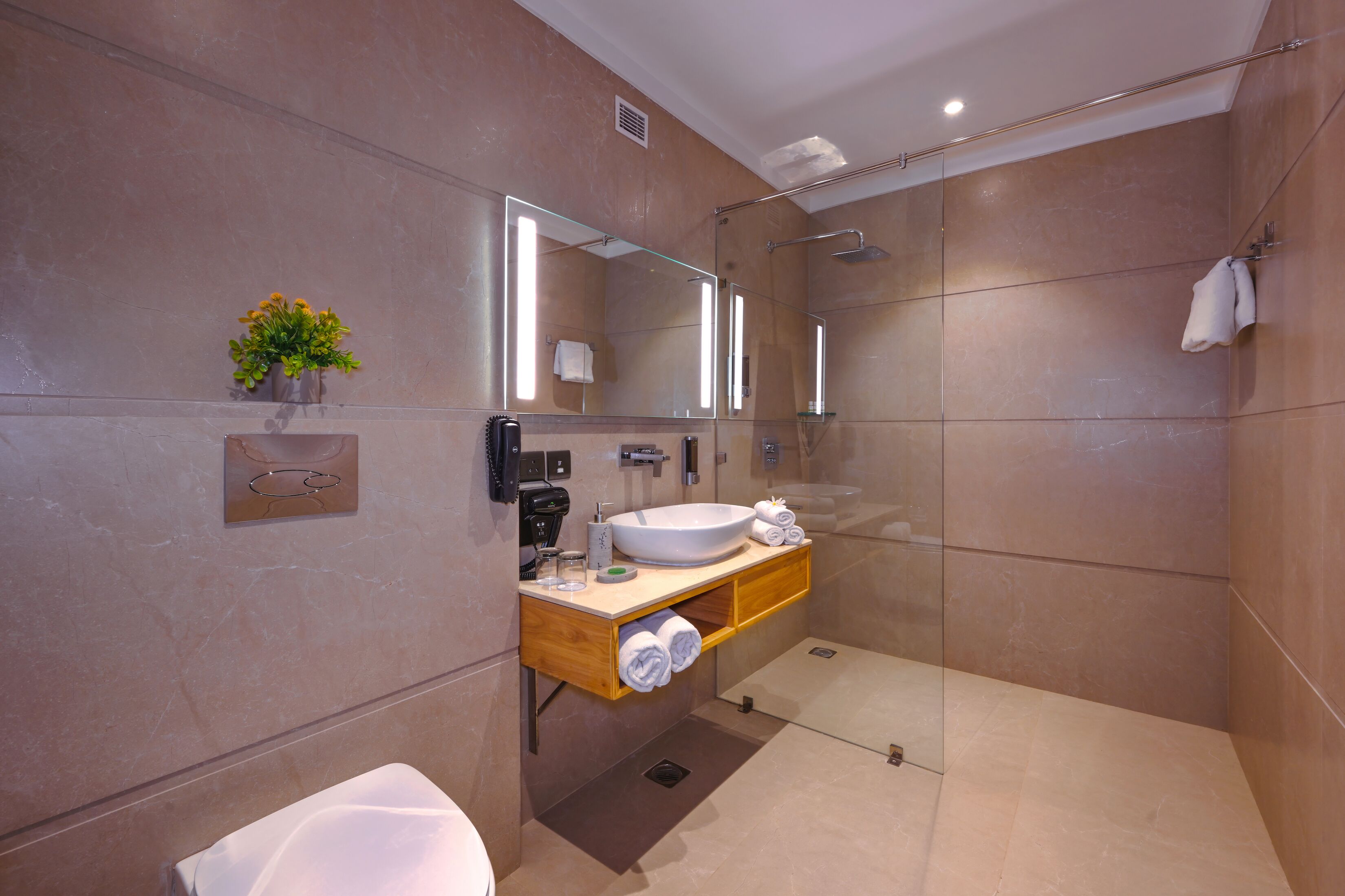Un baño moderno con un espejo grande, un lavabo, una ducha y un inodoro.
