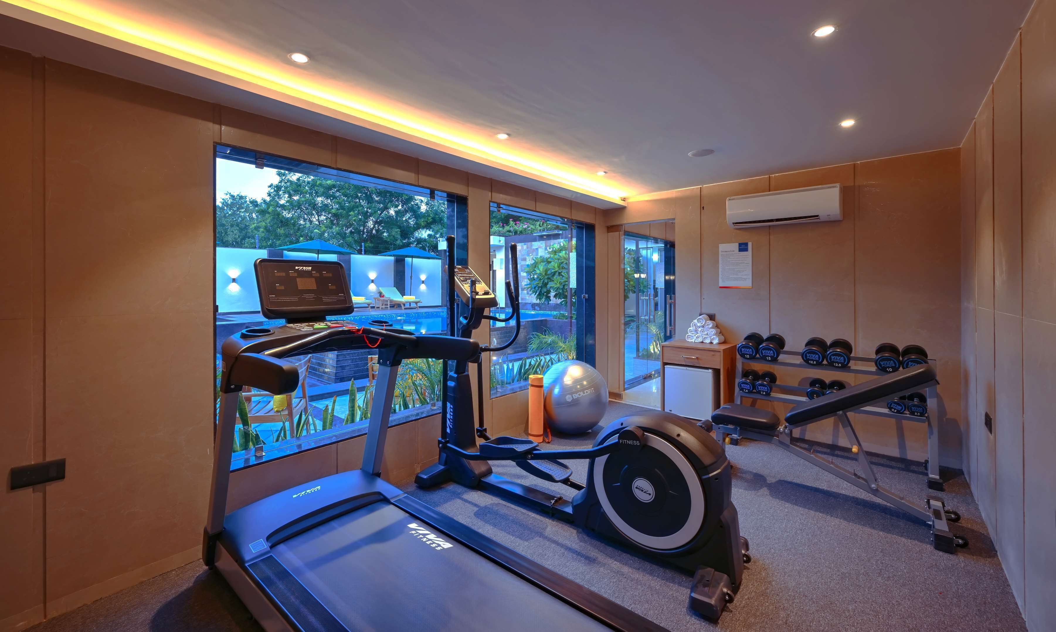 A gym with a treadmill, exercise bike, and dumbbells.