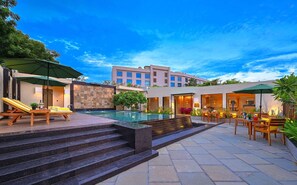 Un hotel moderno con piscina, asientos al aire libre y una escalera que conduce al área de la piscina.