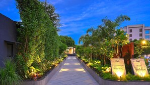 A pathway leading to a building with a swimming pool, gym, and spa. - Royale Sarovar Portico Agra (Agra)