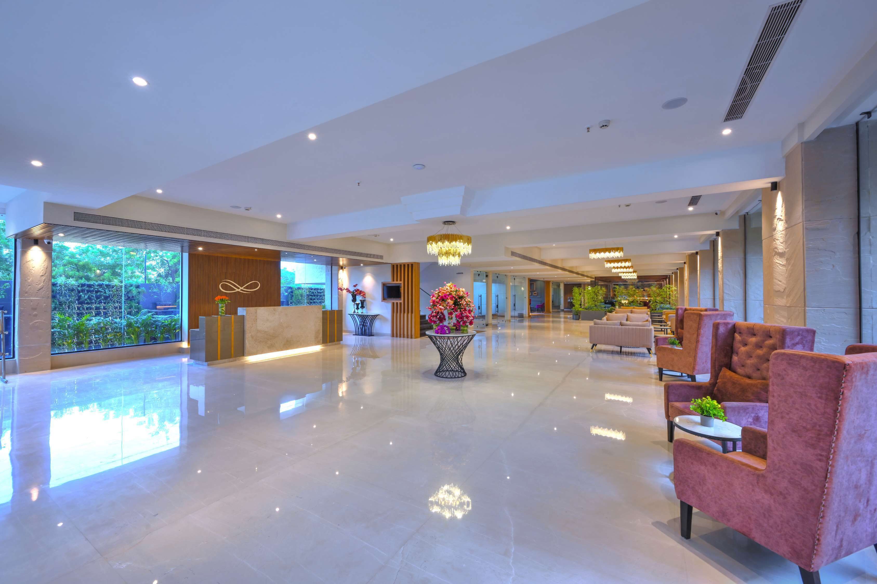 A spacious lobby with a reception desk, seating area, and a large window overlooking greenery.