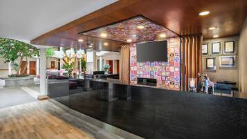 Un vestíbulo de hotel con mostrador de recepción, zona de estar y una pared decorada con diseños coloridos.