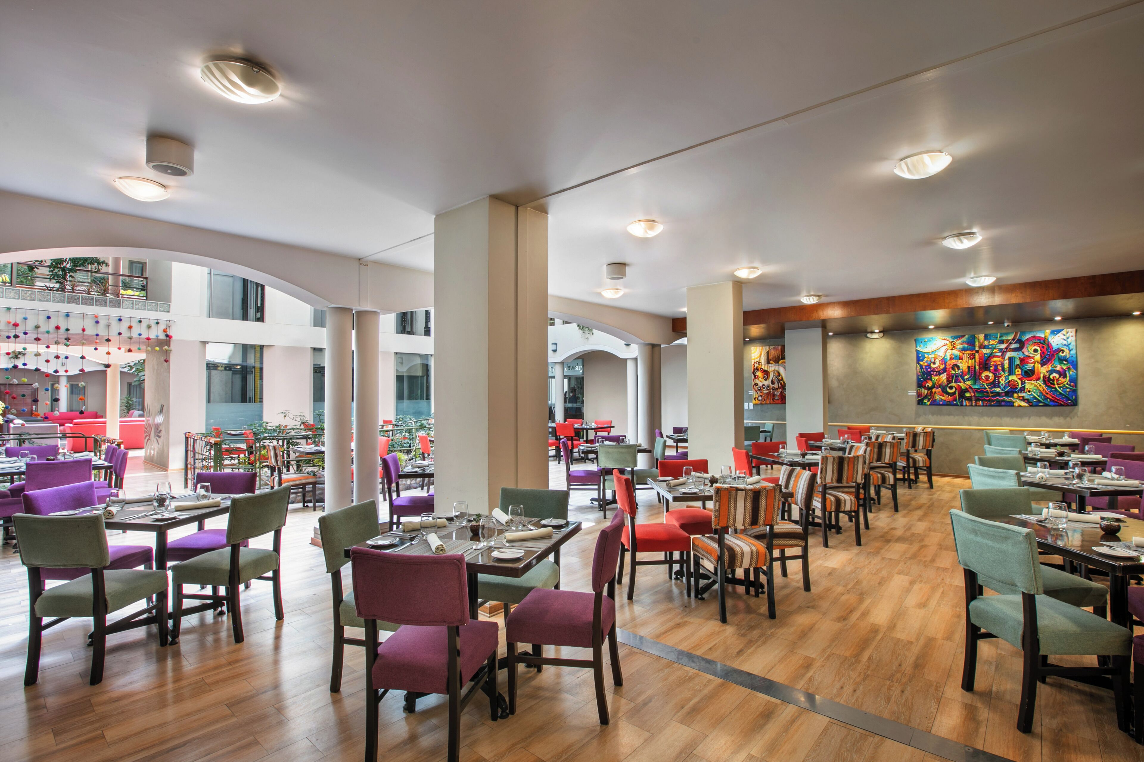 A spacious restaurant with multiple dining areas, high ceilings, and modern lighting.