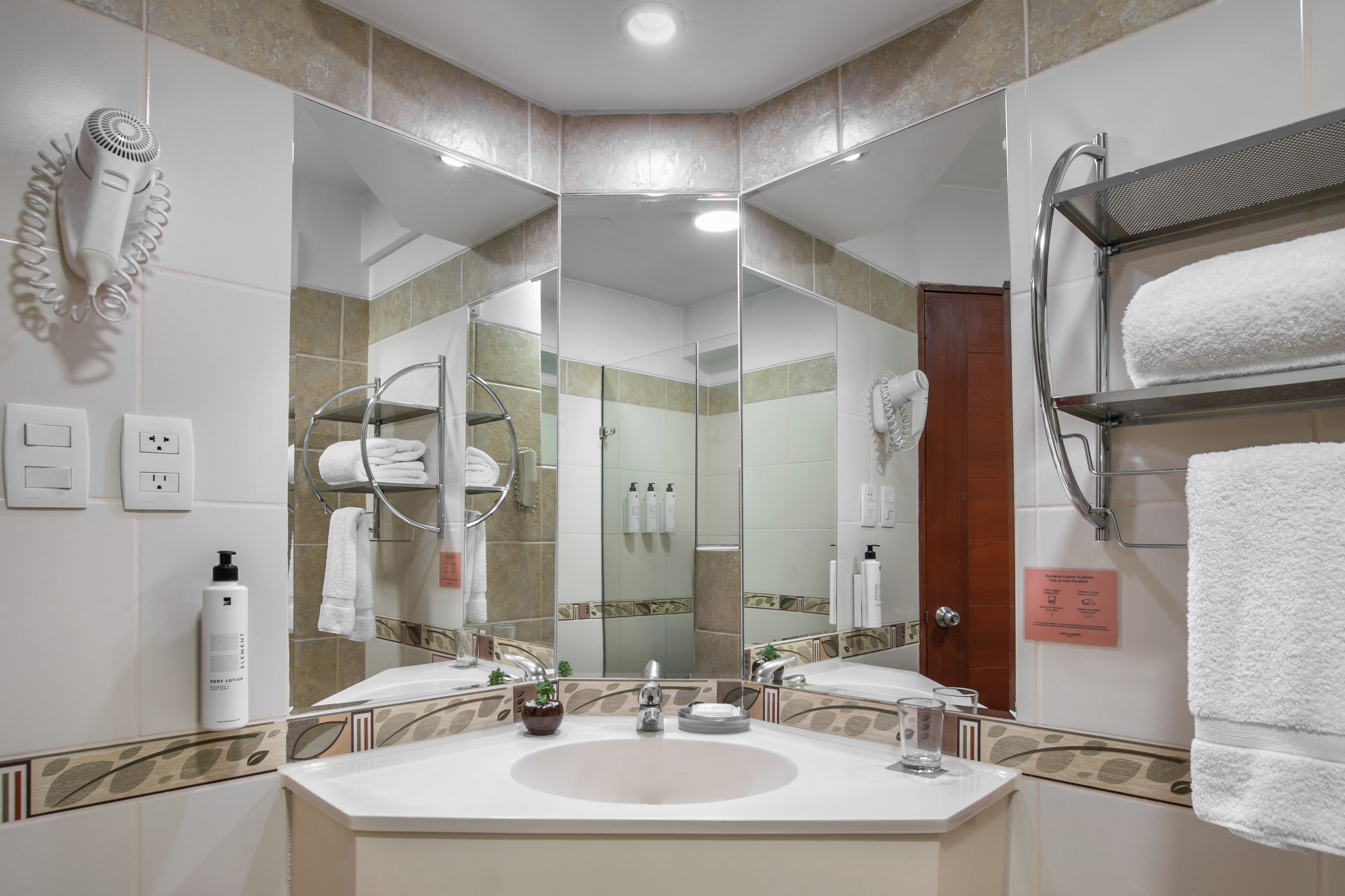 A modern bathroom with a large mirror, dual sinks, and a towel rack.