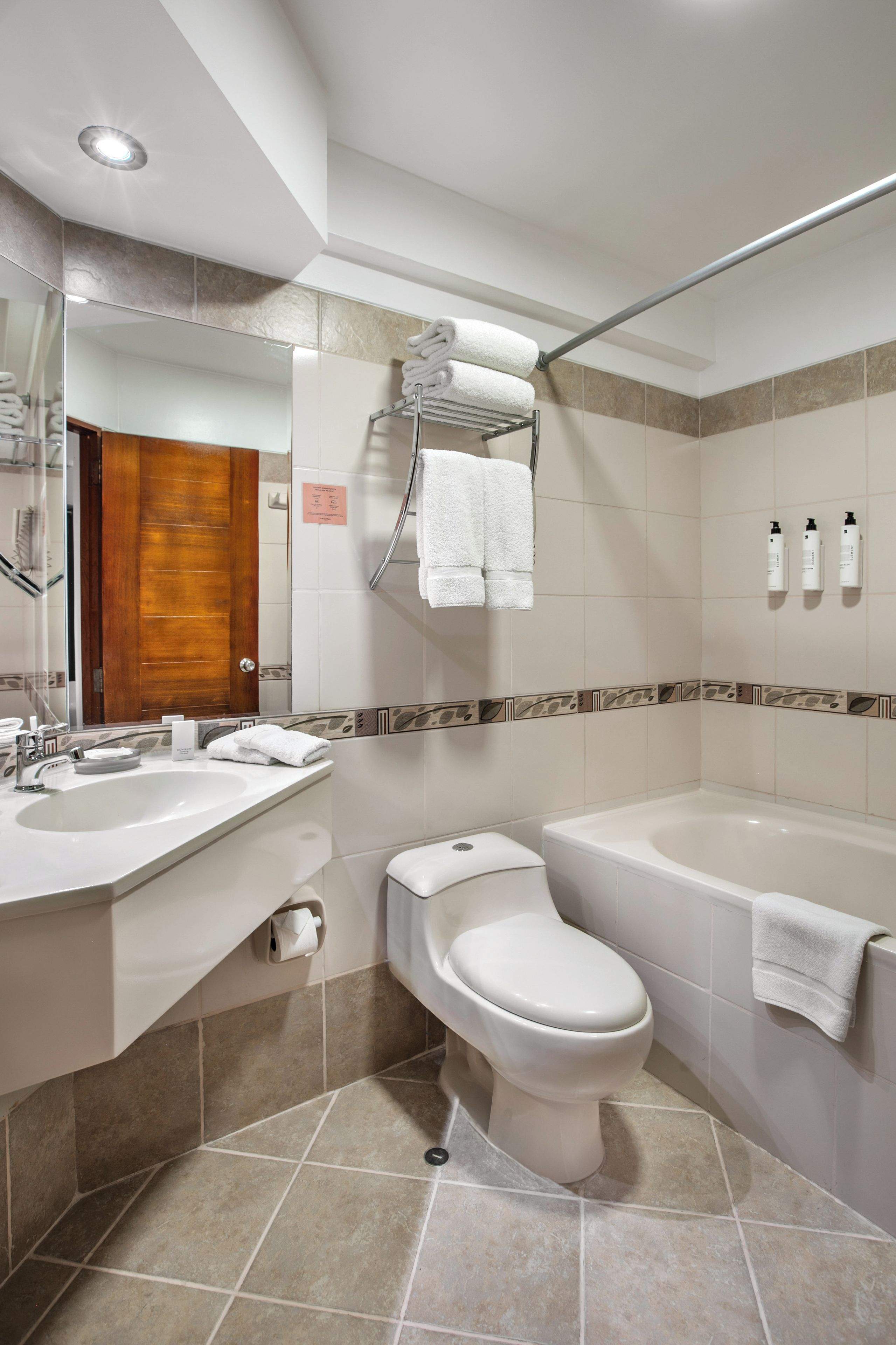 A modern bathroom with a double sink, toilet, and bathtub.