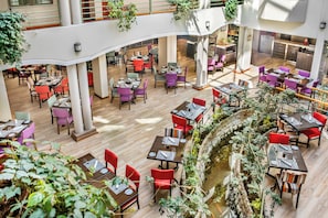 A multi-level dining area with tables and chairs, a central water feature, and indoor plants. - Hotel Cusco La Paccha, Affiliated by Meliá (Cusco)