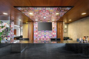 A reception area with a black reception desk, a flat-screen TV mounted on the wall, and a colorful patterned ceiling. - Hotel Cusco La Paccha, Affiliated by Meliá (Cusco)