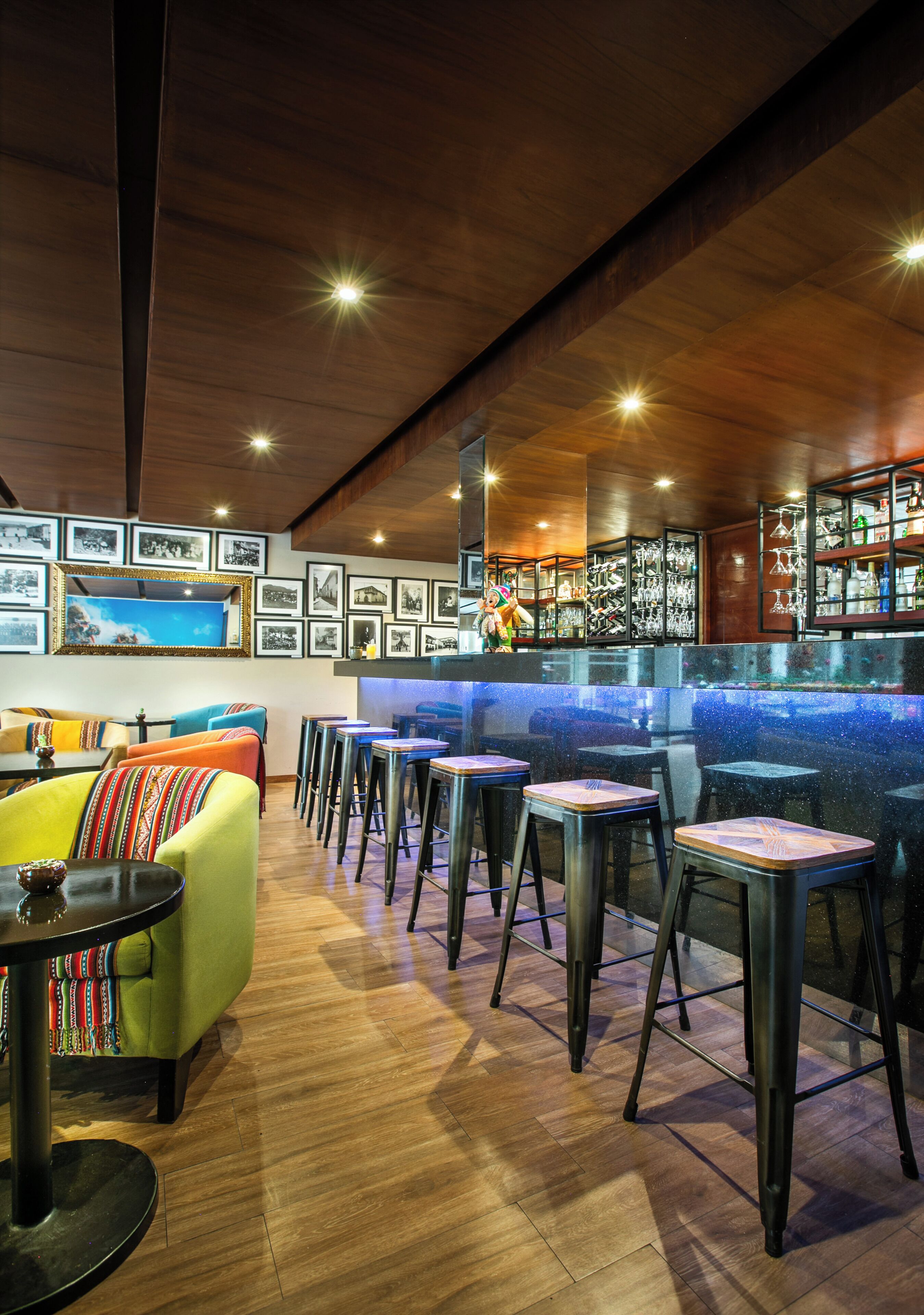 A bar area with stools, a counter, and a wall of framed photos.