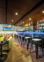 Una zona de bar con taburetes, mostrador y una pared de fotos enmarcadas.
