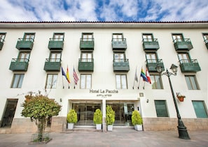 Fachada de hotel con varios balcones, banderas y cielo despejado.