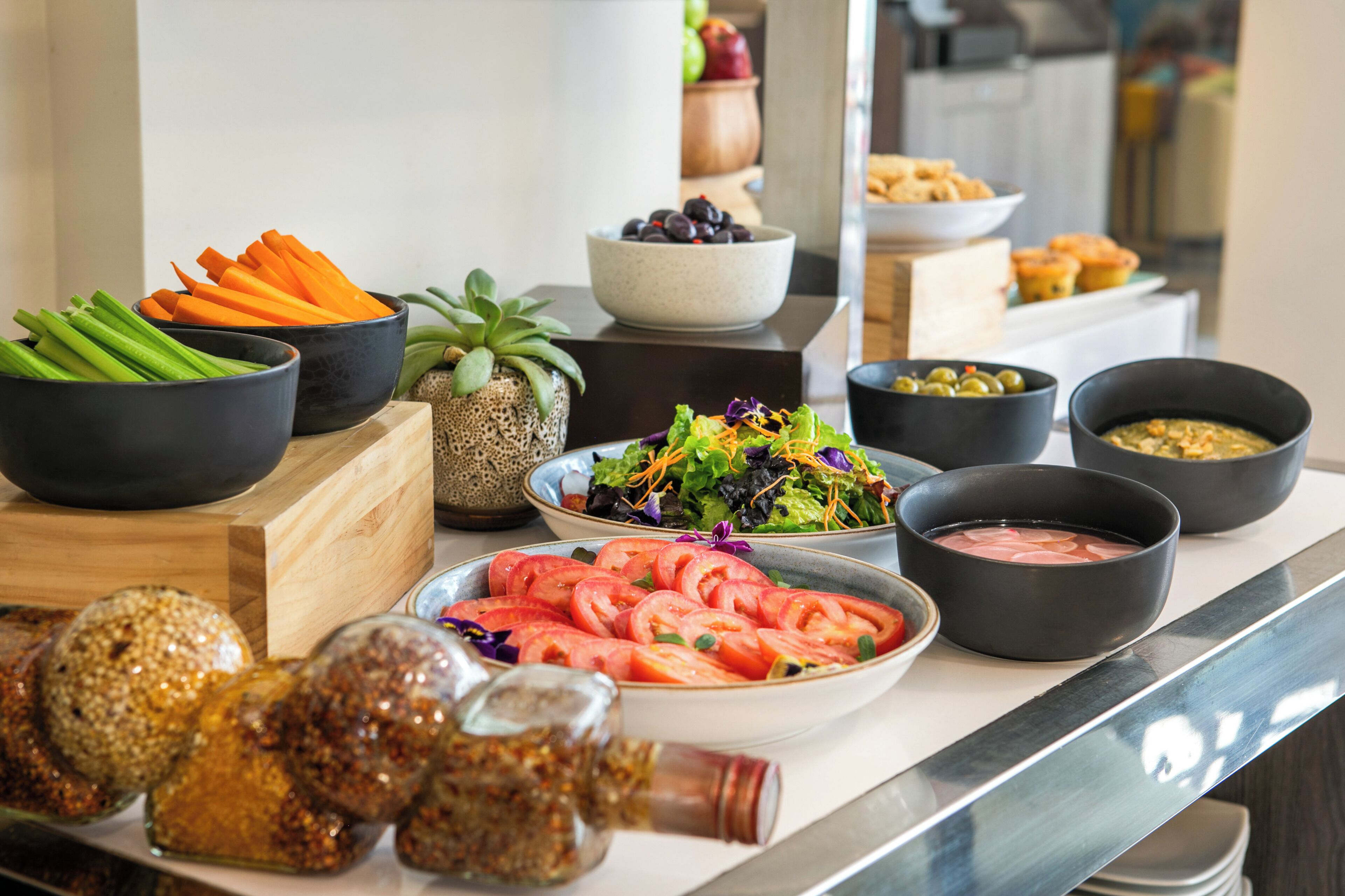 A buffet table with various food items including vegetables, salads, and dips.
