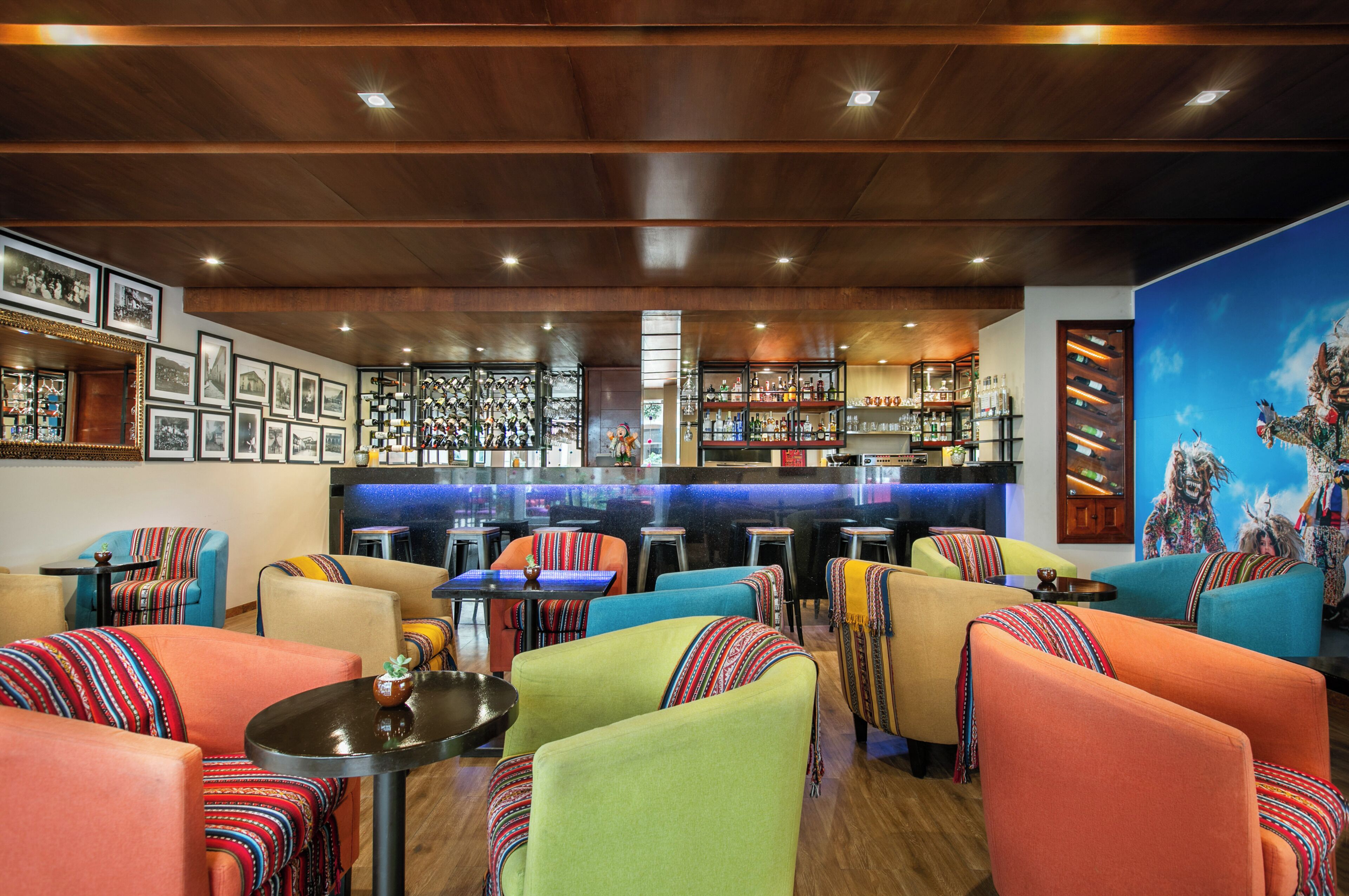 A bar area with a counter and stools, surrounded by colorful seating with patterned cushions.