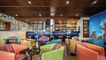 A bar area with a counter and stools, surrounded by colorful seating with patterned cushions.