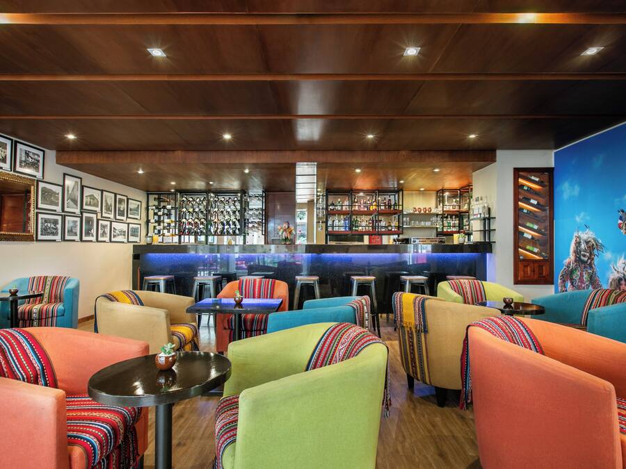 A bar area with a counter and stools, surrounded by colorful seating with patterned cushions.