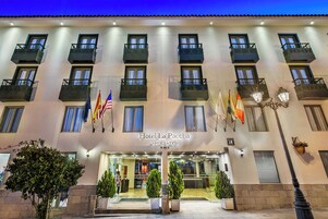 A hotel facade with multiple balconies, flags, and a well-lit entrance.