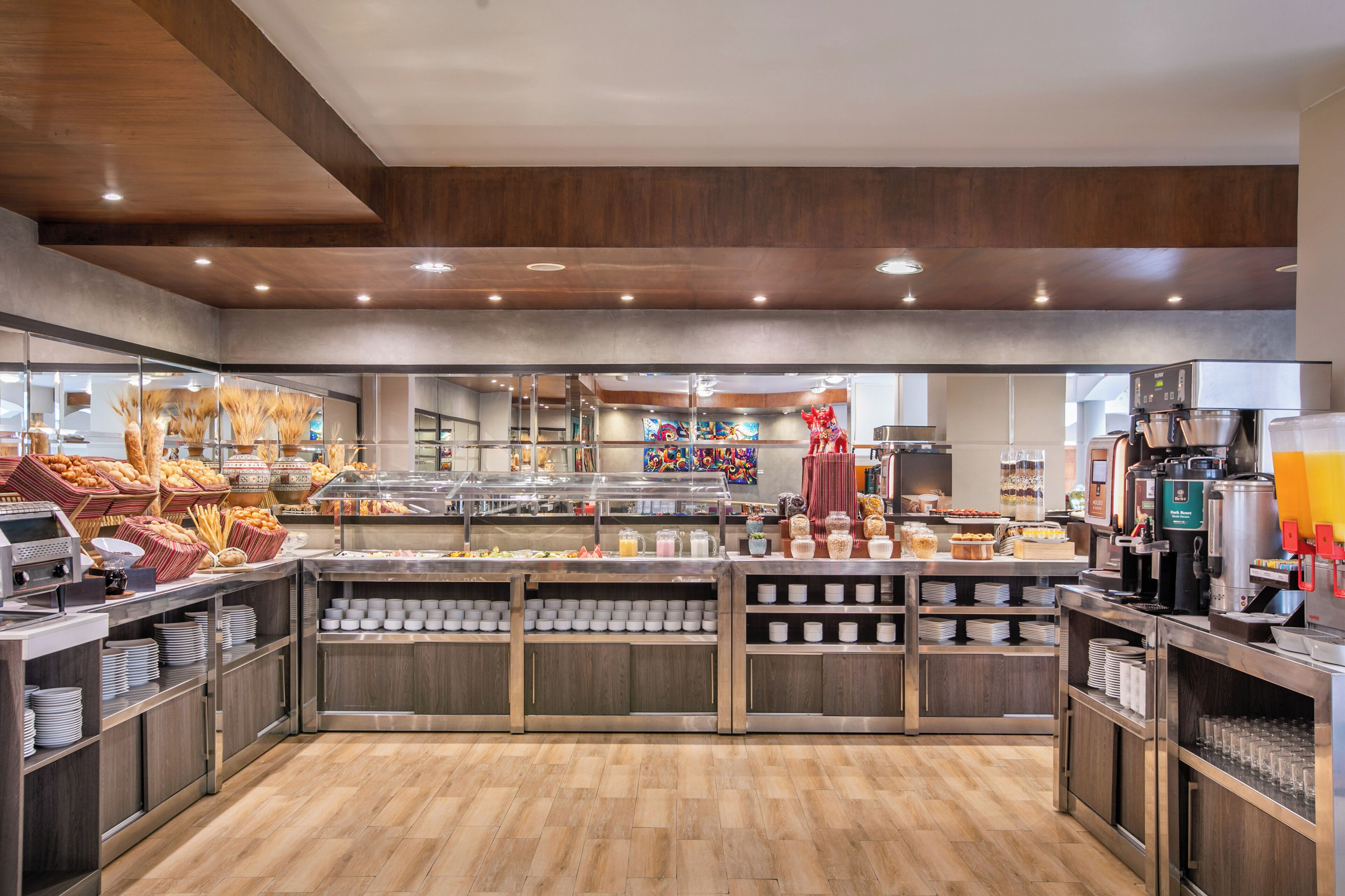 Un buffet de petit-déjeuner moderne proposant une variété de plats, un coin café et une statue décorative.
