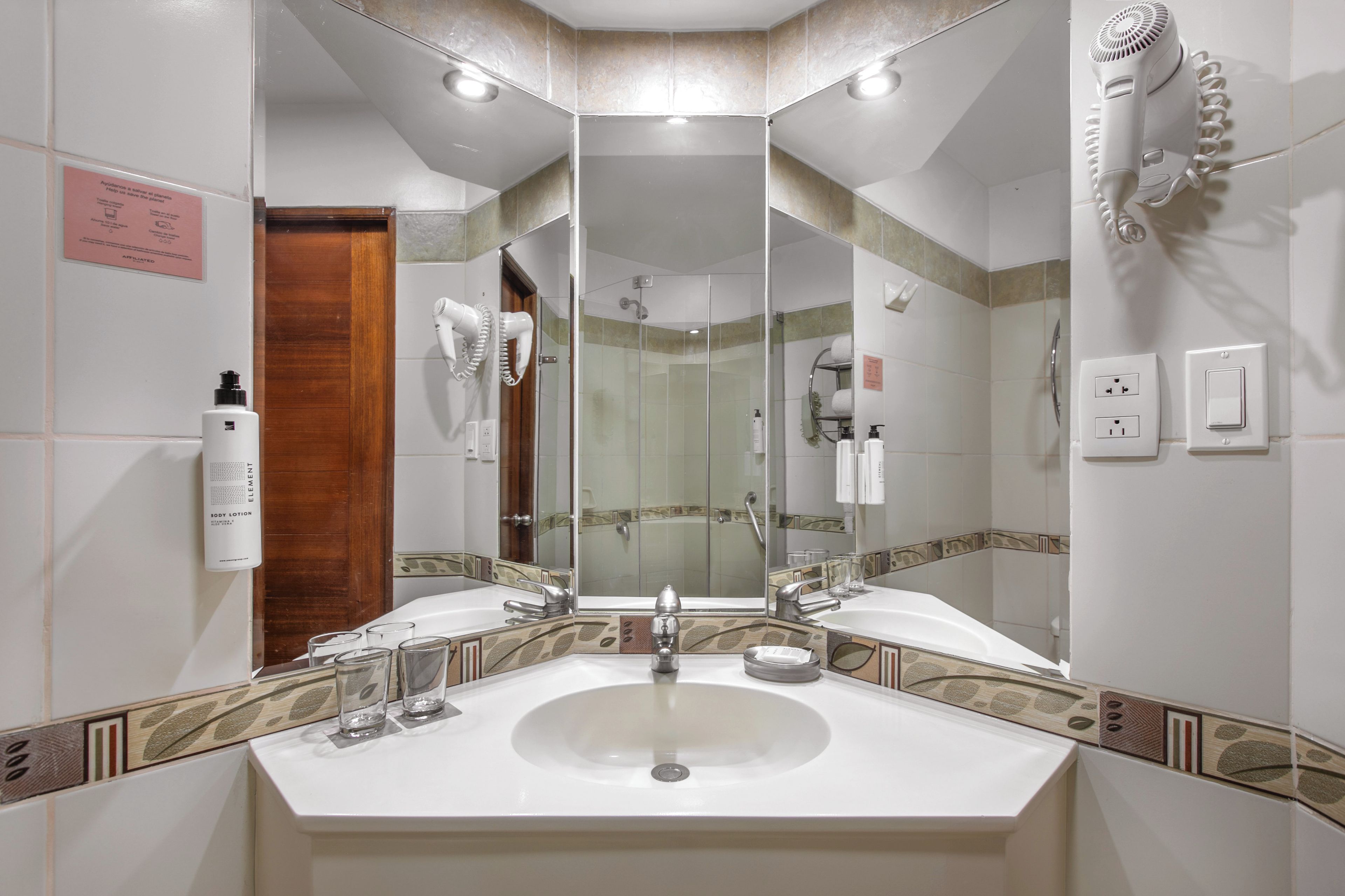 Un baño con un espejo grande, un lavamanos y una zona de ducha.