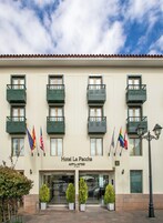 Un hotel con fachada plana, varios balcones y banderas.