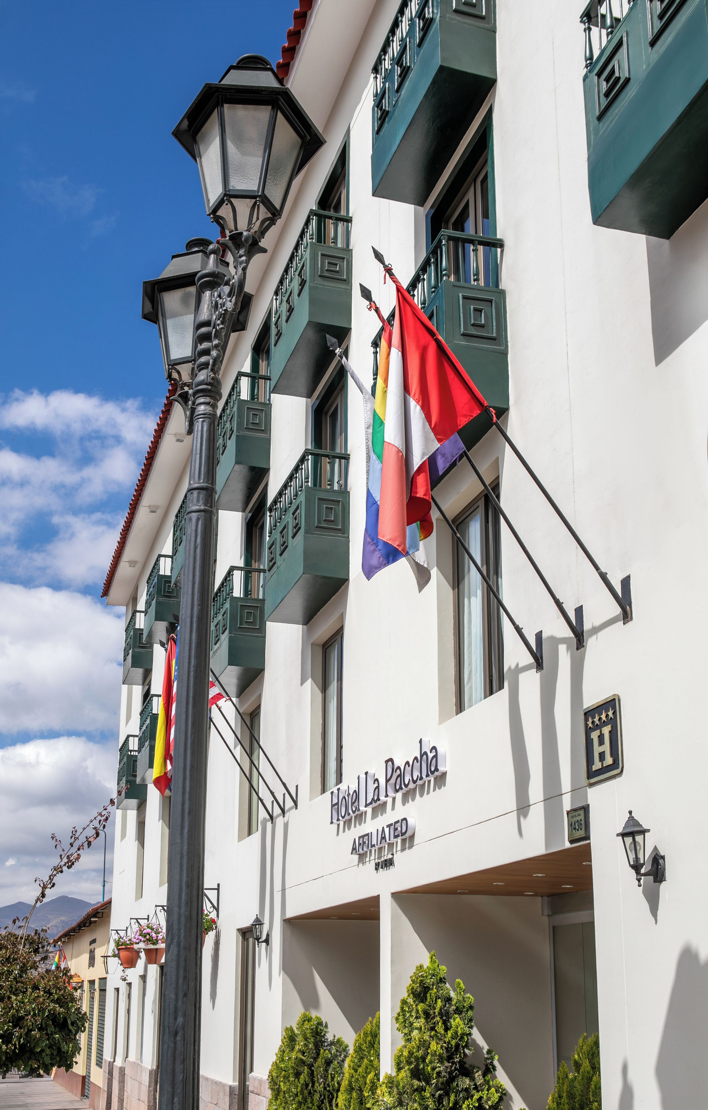 A hotel facade with multiple flags, balconies, and a clear sky.