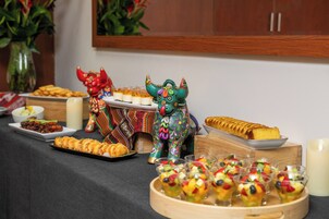 A buffet table with various food items, including a tray of cookies, a plate of desserts, and fruit cups.