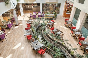 A multi-level dining area with tables and chairs, a central water feature, and a view of the kitchen and dining area in the background.