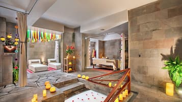 A spa-like setting with a stone floor, a wooden staircase, and a bed with a white canopy.