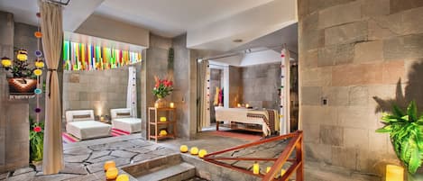 Un ambiente tipo spa con suelo de piedra, escalera de madera y cama con dosel blanco.