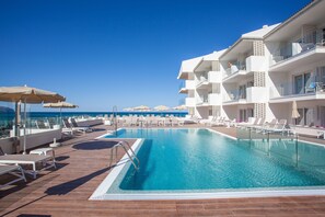 Una piscina al aire libre, sombrillas, sillones reclinables de piscina