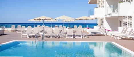 Een buitenzwembad, parasols voor strand/zwembad