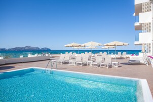 Una piscina al aire libre, sombrillas, sillones reclinables de piscina