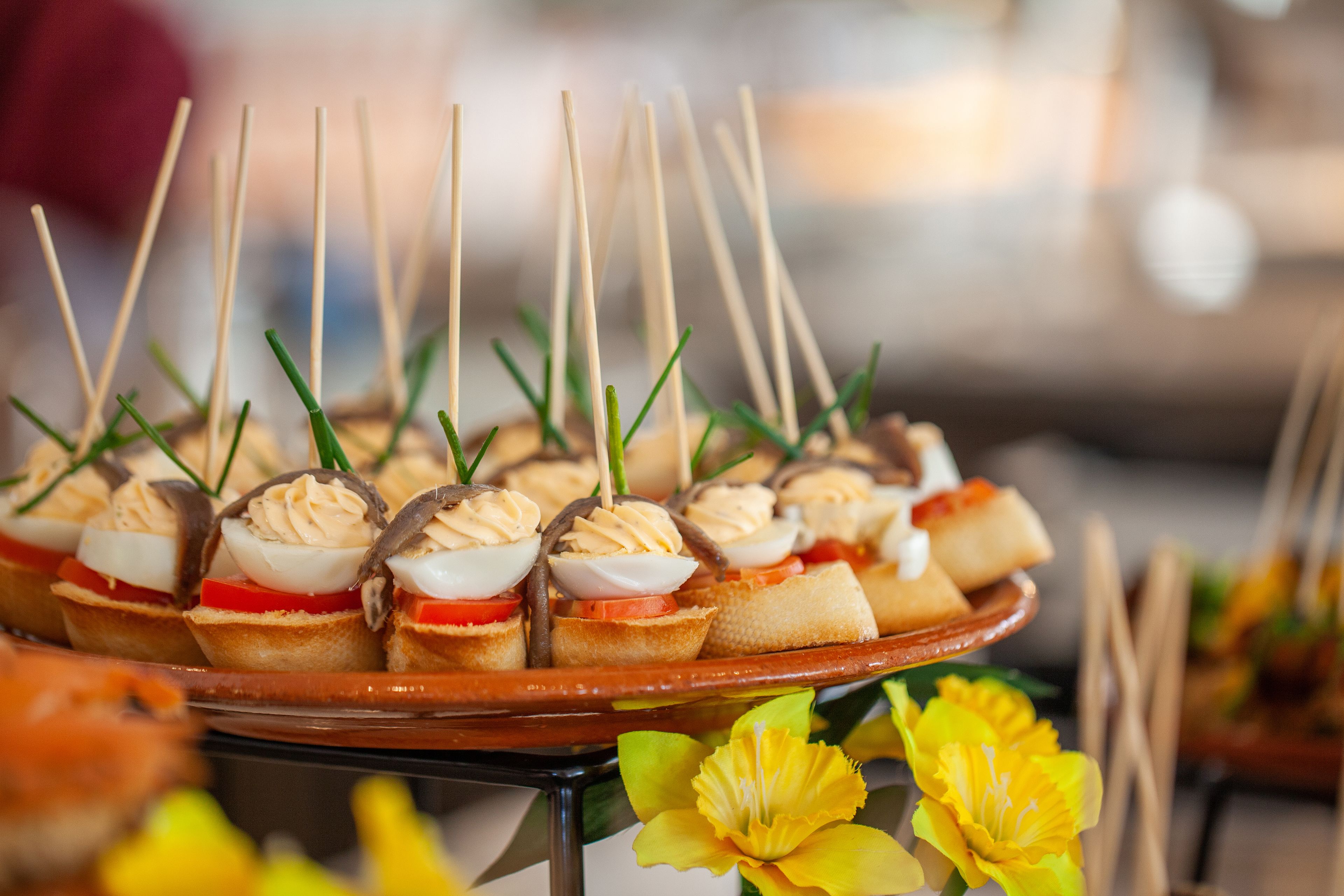 A tray of appetizers with toothpicks, including items with eggs, cream, and vegetables.